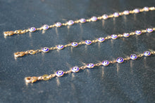 Load image into Gallery viewer, Gold chain with blue evil eye charms on a dark surface